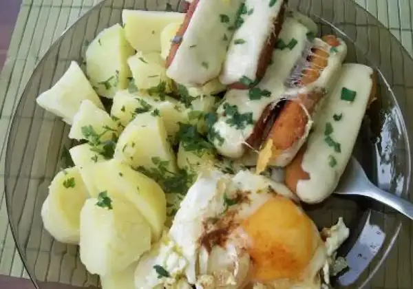 Talerz z ziemniakami, jajkiem sadzonym i paluszkami rybnymi w serze.
