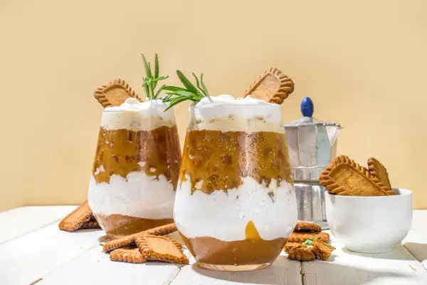 Dwa szklanki kawy z bitą śmietaną, ciasteczkami Biscoff i rozmarynem.